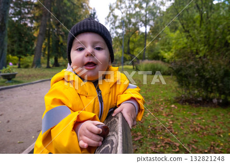 Toddler in Yellow Raincoat Enjoying Park Toddler in Yellow Raincoat Enjoying Park 132821248