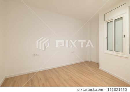Empty room with white walls and wooden flooring. A single window allows natural light to enter. The space is minimalistic and ready for decoration. Empty room with white walls and wooden flooring. A single window allows natural light to enter. The space is minimalistic and ready for decoration. 132821350