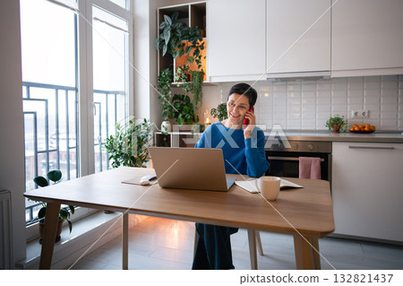 Mature woman smiling while on business call, work on laptop at home. Remote work, self employed job Mature woman smiling while on business call, work on laptop at home. Remote work, self employed job 132821437