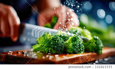 Close-up of fresh broccoli being sliced on a wooden board, with droplets and motion captured mid-cut 132821555