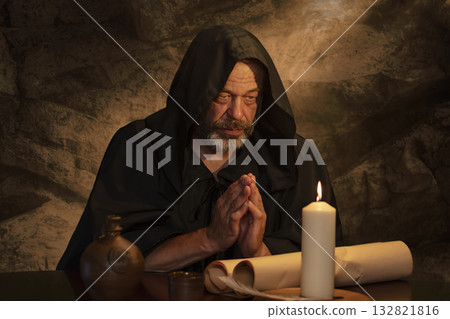 Handwriting and prayer in ancient times - a scene with a monk and parchment. 132821816