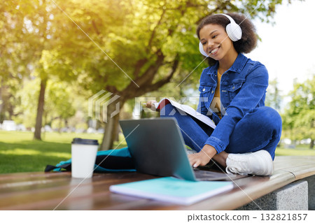 Happy black female student study outdoors with laptop and workbooks Happy black female student study outdoors with laptop and workbooks 132821857