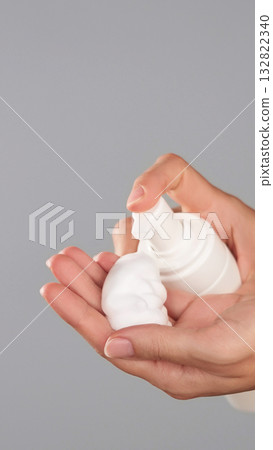 Close-up of female hands dispensing white foam from bottle into the palm. Product application during daily skincare and beauty routine. Foaming Facial Cleanser cosmetic product advertising copy space Close-up of female hands dispensing white foam from bottle into the palm. Product application during daily skincare and beauty routine. Foaming Facial Cleanser cosmetic product advertising copy space 132822340