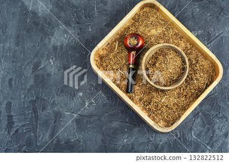 Smoking pipe with tobacco on a table. Smoking pipe with tobacco on a table. 132822512