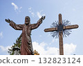 Majestic Jesus statue with outstretched arms beside ornate cross 132823124
