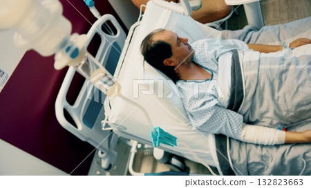 Close-up view of intravenous drip valve and infusion system in hospital room with patient in background, showing modern healthcare equipment and sterile environment Close-up view of intravenous drip valve and infusion system in hospital room with patient in background, showing modern healthcare equipment and sterile environment 132823663