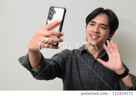 Portrait of handsome Young Asian Thai man using phone against white background Portrait of handsome Young Asian Thai man using phone against white background 132824173