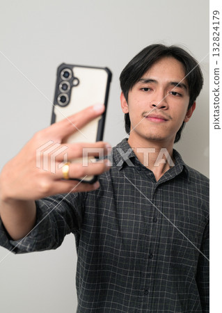 Portrait of handsome Young Asian Thai man using phone against white background 132824179