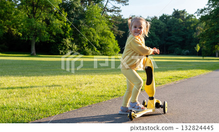 Child with scooter. Yellow riding toddler fun. Summer activity outdoor road. 132824445