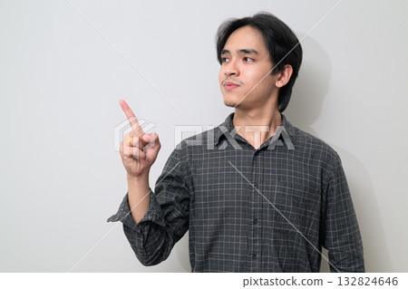 Portrait of handsome Young Asian Thai man pointing finger against white background Portrait of handsome Young Asian Thai man pointing finger against white background 132824646