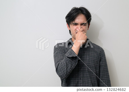 Portrait of handsome Young Asian Thai man disgusted holding nose against white background Portrait of handsome Young Asian Thai man disgusted holding nose against white background 132824682