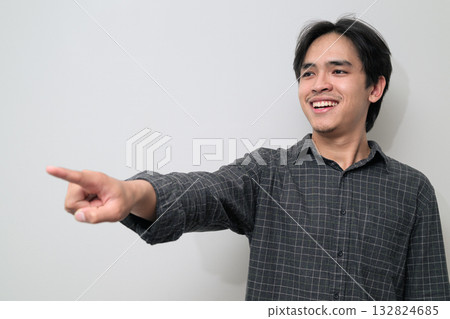 Portrait of handsome Young Asian Thai man pointing finger against white background Portrait of handsome Young Asian Thai man pointing finger against white background 132824685