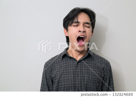 Portrait of handsome Young Asian Thai man yawning while tired against white background 132824689