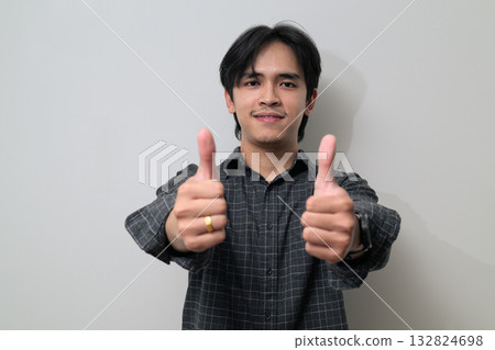 Portrait of handsome Young Asian Thai man giving thumbs up against white background 132824698