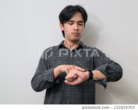 Portrait of handsome Young Asian Thai man using smartwatch against white background Portrait of handsome Young Asian Thai man using smartwatch against white background 132824703