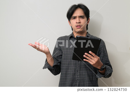 Portrait of handsome Young Asian Thai man using digital tablet computer against white background Portrait of handsome Young Asian Thai man using digital tablet computer against white background 132824730