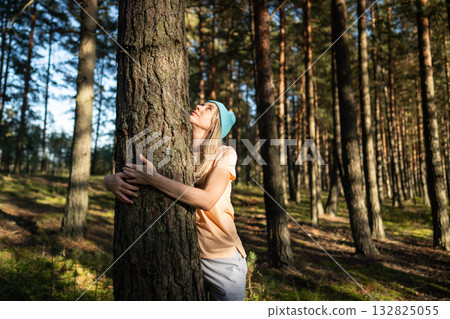 Satisfied woman hugging tree trunk while look up into canopy in quiet forest. Mindfulness in nature 132825055
