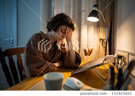 Sleepy exhausted young woman cradles face in hands after night work. Overwhelmed millennial Sleepy exhausted young woman cradles face in hands after night work. Overwhelmed millennial 132825081