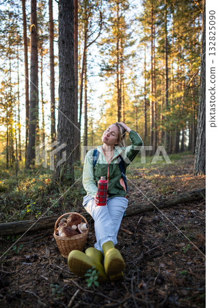 Relaxed woman resting after mushroom foraging breathing fresh air and drinking tea on solo travel Relaxed woman resting after mushroom foraging breathing fresh air and drinking tea on solo travel 132825090