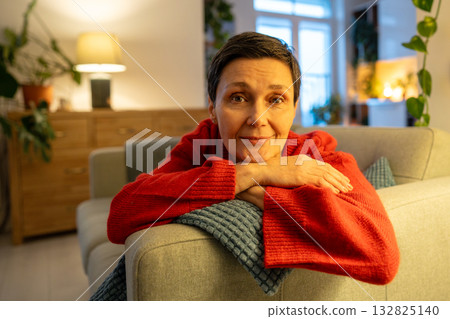 Smiling mature woman resting head on hands. Happy female looking camera on sofa, graceful retirement Smiling mature woman resting head on hands. Happy female looking camera on sofa, graceful retirement 132825140
