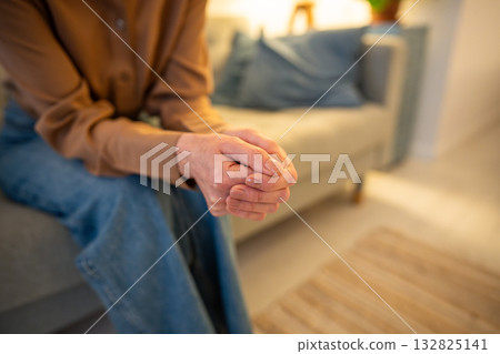 Nervous unrecognizable woman sits on sofa with arms tightly crossed in therapy session counseling Nervous unrecognizable woman sits on sofa with arms tightly crossed in therapy session counseling 132825141