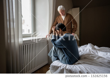 Grieving woman hiding face in hands. Compassionate sad husband comforting her on bed, couple loss 132825156
