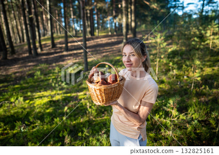 Content female forager showing basket with white boletus mushrooms. Accomplished success of forager 132825161