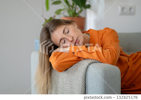 Serene middle-aged woman napping on sofa conveying state of ultimate calm, relaxation and silence 132825176