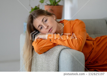 Middle-aged woman feelings of melancholy due to difficulties with loved one lying on home sofa 132825197