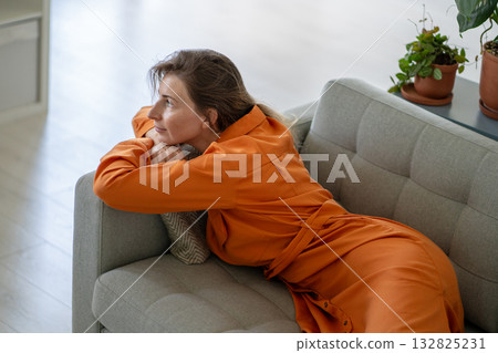 Relaxed middle-aged woman dreaming, fantasizing savoring memories lying comfortably on home couch Relaxed middle-aged woman dreaming, fantasizing savoring memories lying comfortably on home couch 132825231