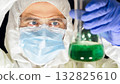 Dedicated scientist examining green liquid in lab. 132825610
