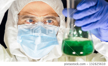 Dedicated scientist examining green liquid in lab. Dedicated scientist examining green liquid in lab. 132825610