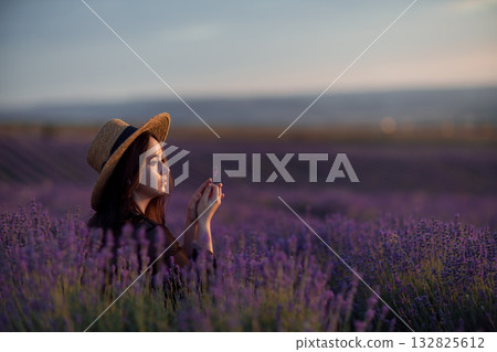 Woman lavender sunset holding flower in straw hat amidst purple field Woman lavender sunset holding flower in straw hat amidst purple field 132825612