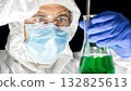 Dedicated scientist examining green liquid in lab. 132825613