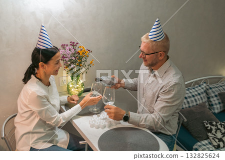 Couple Birthday Party Celebration: Indoor intimate birthday celebration for a couple, enjoying drinks at home. 132825624