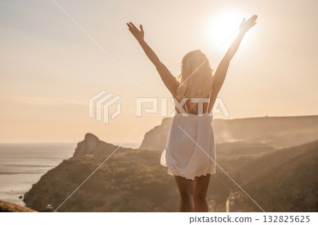 A woman is standing on a hill overlooking a body of water. She is wearing a white dress and she is happy. A woman is standing on a hill overlooking a body of water. She is wearing a white dress and she is happy. 132825625