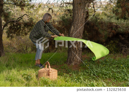 Woman rolling yoga mat preparing for exercise in green forest nature park Woman rolling yoga mat preparing for exercise in green forest nature park 132825638