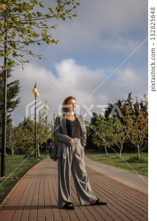 Woman, Park, Path - Woman standing on a path in a park wearing a gray suit. 132825648