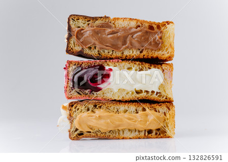 Stack of filled croissant halves with chocolate, cherry and caramel cream on white background 132826591