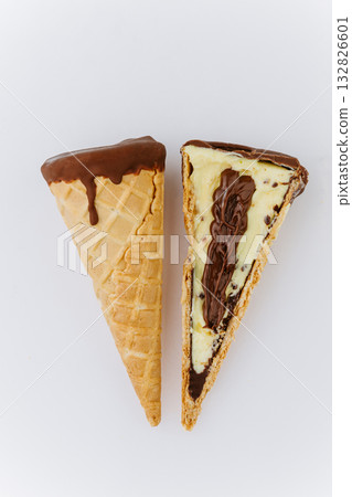 Sliced chocolate and vanilla ice cream cone with creamy filling on white background 132826601