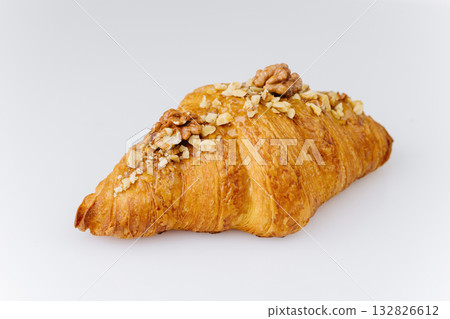 Golden croissant topped with caramel glaze and crunchy walnut pieces on white background 132826612