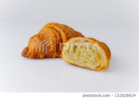 Fresh flaky croissant with airy layers, cut in half, isolated on white background 132826624