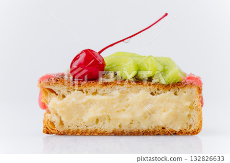 Close-up of a fruit Danish pastry with kiwi, orange slices, and cherry on pink icing 132826633