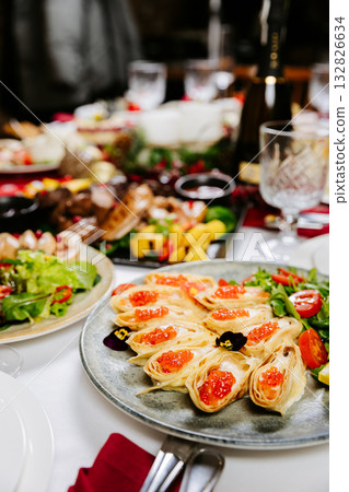 Festive crepe rolls with red caviar, greens and cherry tomatoes on elegant table setting Festive crepe rolls with red caviar, greens and cherry tomatoes on elegant table setting 132826634