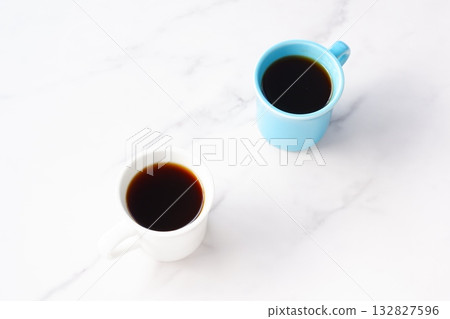 An image of two people having a meeting while drinking coffee from two mugs filled with freshly brewed coffee 132827596
