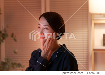 一位女士在夜間塗抹潤膚霜 132828043