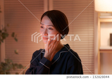 一位女士在夜間塗抹潤膚霜 一位女士在夜間塗抹潤膚霜 132828044