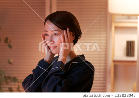 一位女士在夜間塗抹潤膚霜 一位女士在夜間塗抹潤膚霜 132828045