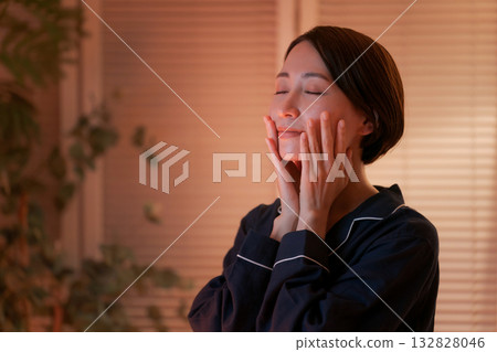 一位女士在夜間塗抹潤膚霜 一位女士在夜間塗抹潤膚霜 132828046