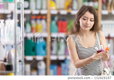 Girl in summer dress chooses nail polish in a supermarket 132828187